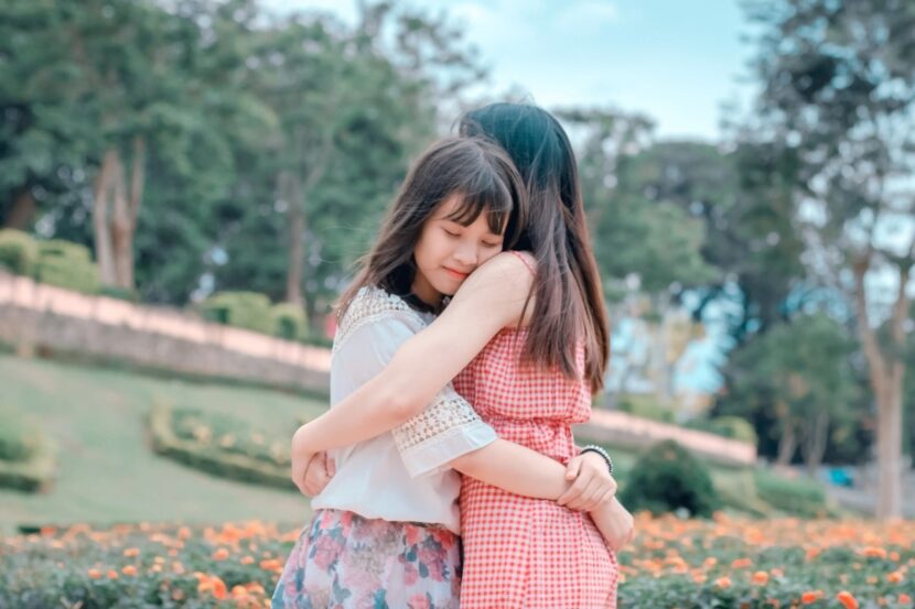 Two girls hugging each other.