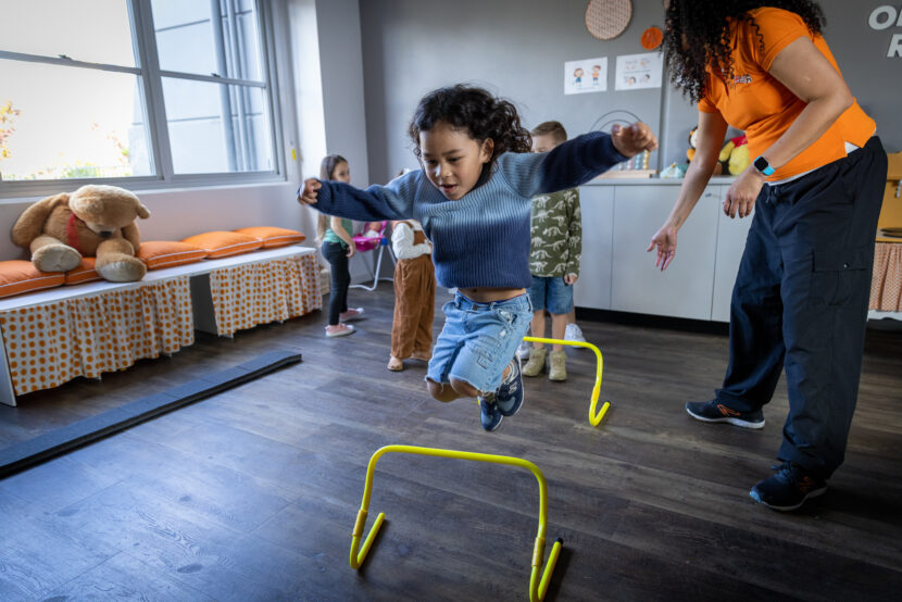 child jumping a hurdle in a play based fitness program