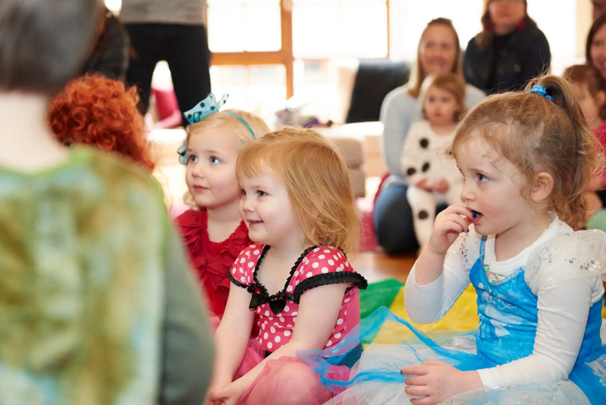 Toddlers in costumes sitting together at a themed bday party.